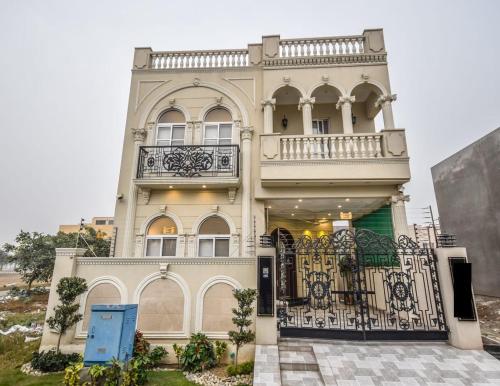 a large white house with a balcony and a gate at Luxury Dream Vacation Home in DHA Near Lahore Airport in Lahore