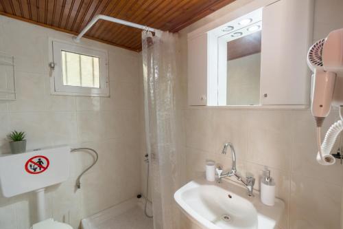 y baño con lavabo, aseo y espejo. en Villa Kostas, en Vitalades
