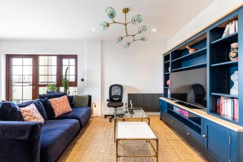 City View Spacious 2 bedroom Penthouse في لندن: غرفة معيشة مع أريكة زرقاء وتلفزيون