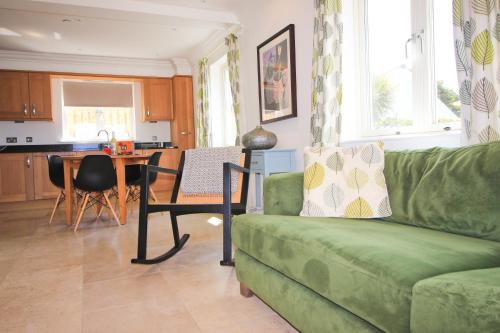 a living room with a green couch and a table at STYLISH, BEACHSIDE apartment, sea views in St Merryn