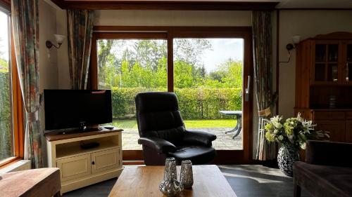 a living room with a chair and a television at Camping Boslust, Bungalow de Koekoek in Putten