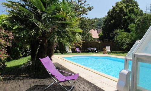 une chaise violette assise à côté de la piscine dans l'établissement Grande maison avec jardin, tennis et piscine privés dans le calme dun vieux village lotois, à Strenquels