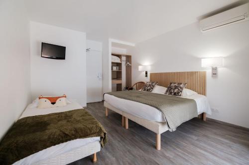 a bedroom with two beds and a tv on the wall at Anglade Hotel in Le Lavandou