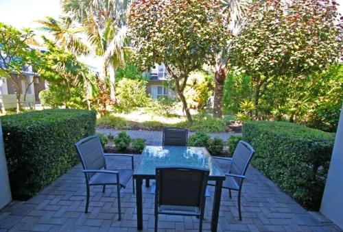 a table and chairs on a patio with trees at Apartment in Apollo Quays resort with shared Jetty in Mandurah