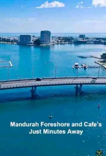 a bridge over the water with a city in the background at Apartment in Apollo Quays resort with shared Jetty in Mandurah