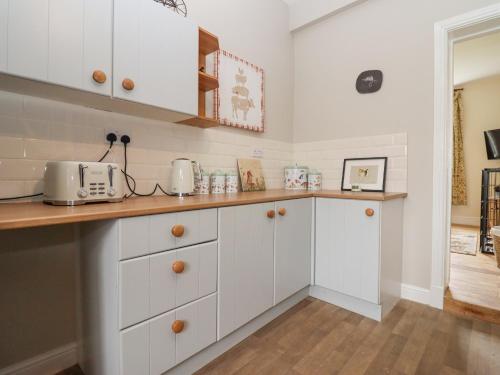 a kitchen with white cabinets and a counter top at The Shires at Bickerscourt in Solihull
