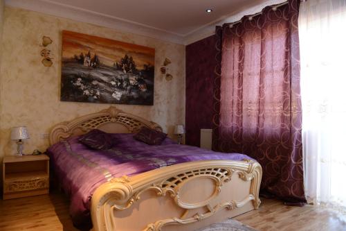 - une chambre avec un grand lit et des draps violets dans l'établissement Vila Perla Sapanteana, à Săpînţa