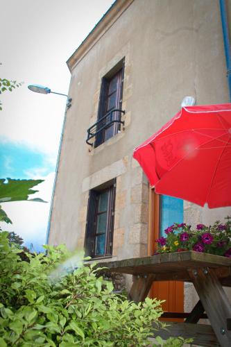 a red umbrella sitting in front of a building at Gîte Le Féodal 3 Etoiles in Tiffauges