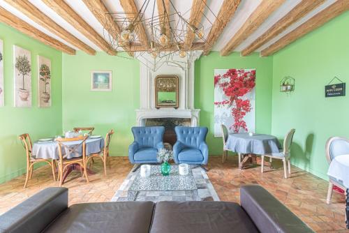 ein Wohnzimmer mit grünen Wänden, einem Sofa und Stühlen in der Unterkunft la Fontaine du Mont in Mûrs-Érigné