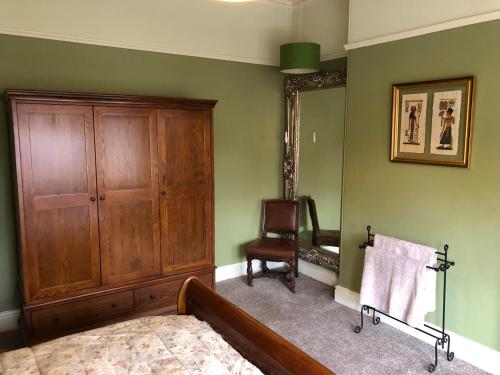 a bedroom with a bed and a cabinet and a chair at Victorian Guest House 200m from the Seafront in West Kirby