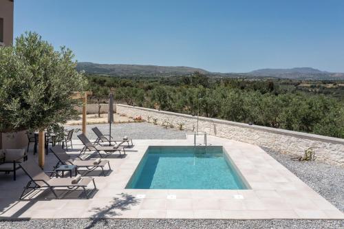 a pool with chairs and a view of a mountain at Meli & Gio 1 in Viranepiskopí
