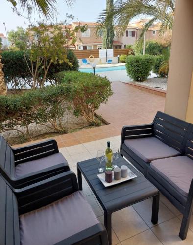 a patio with two chairs and a table with a bottle of wine at MyCyprusStay - Jo's Cosy 1 Bedroom Apartment in Paphos City
