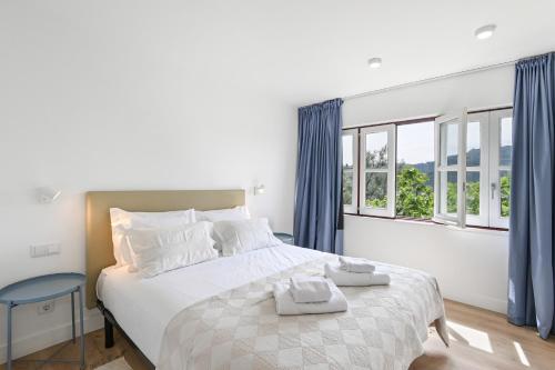a bedroom with a large bed with blue curtains at Quinta Rolim do Bouro By Sé Apartamentos in Roucio