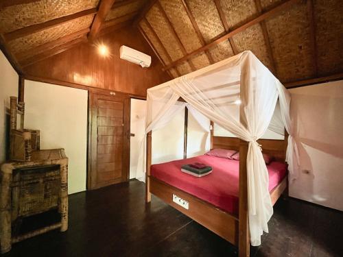 ein Schlafzimmer mit einem Himmelbett in der Unterkunft Little Bear Bungalows in Gili Air