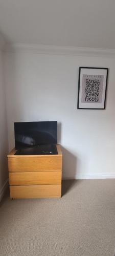 a room with a wooden dresser with a picture on the wall at Carolines rooms in Cherry Hinton