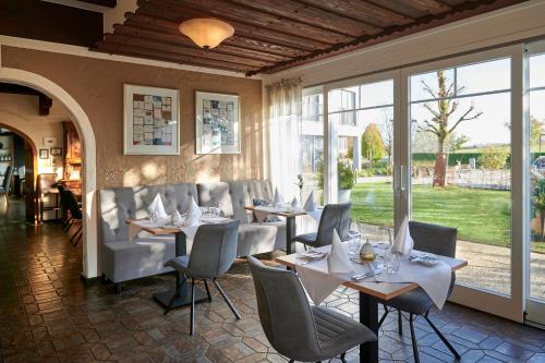 a dining room with tables and chairs and windows at Kucher's Landhotel in Darscheid