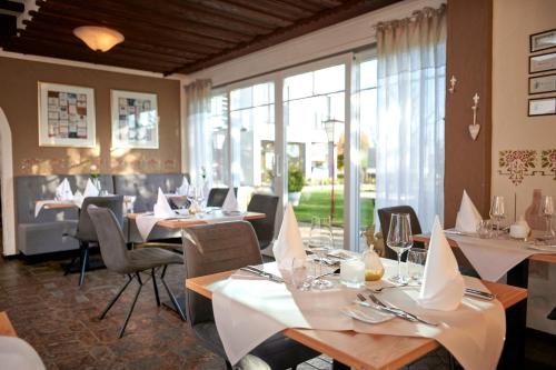 a restaurant with white tables and chairs and windows at Kucher's Landhotel in Darscheid