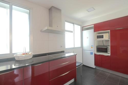 a kitchen with red and white cabinets and windows at Entre Castillo y Catedral VuT 09587 in Burgos
