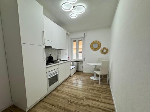 moderna ed elegante Residenza nel centro di Pavia في بافيا: مطبخ فيه دواليب بيضاء وطاولة فيه