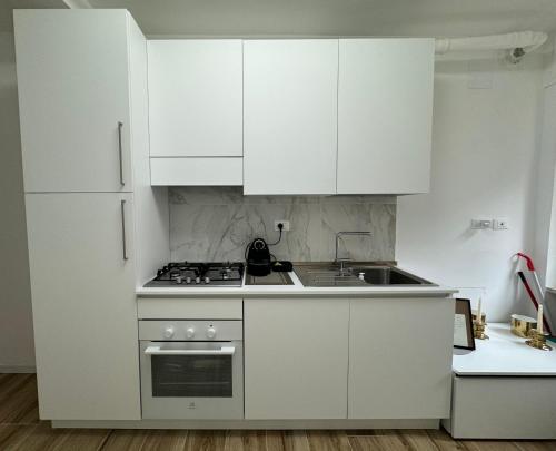 moderna ed elegante Residenza nel centro di Pavia في بافيا: مطبخ أبيض مع دواليب بيضاء ومغسلة