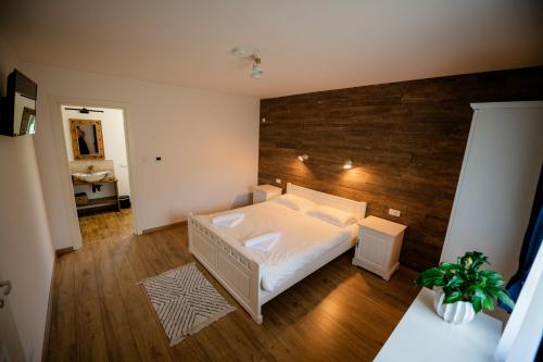 Un dormitorio con una cama blanca y una pared de madera. en La Bunici, en Vişeu de Sus