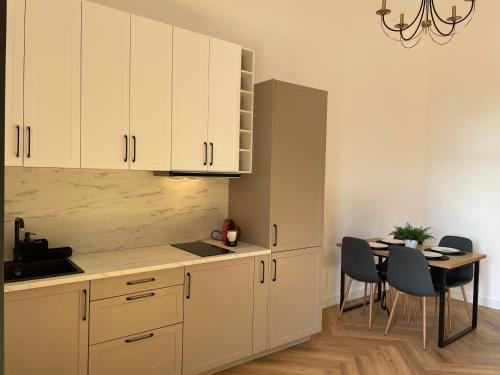 uma cozinha com armários brancos e uma mesa com cadeiras em ALEXANDER FLAT_ALECSANDRI em Oradea
