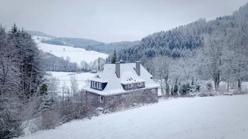uma casa está coberta de neve numa colina em Ferienhaus Stefano em Bad Berleburg