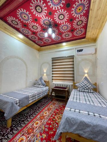 a room with two beds and a red ceiling at Khiva Rajab Ota in Khiva