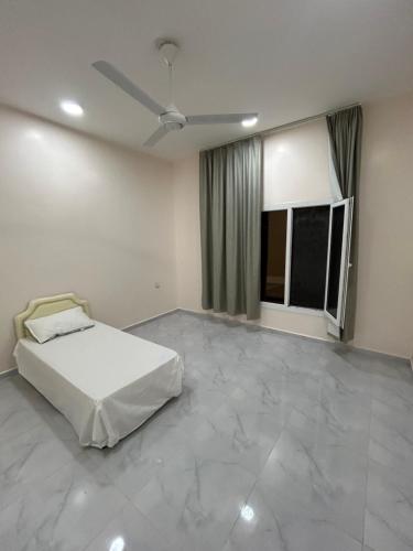 um quarto branco com uma cama e 2 janelas em Najm Chalet em Ḩayl Yaman