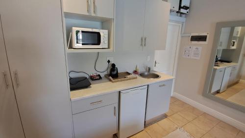a white kitchen with a sink and a microwave at The Dunes Studio 11 in Plettenberg Bay