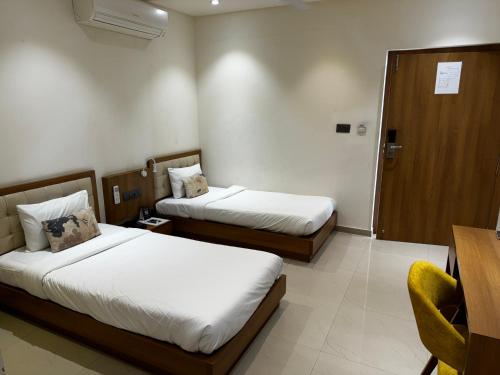 a hotel room with two beds and a chair at Siara Styles Amba Suites, Gandhinagar in Gandhinagar