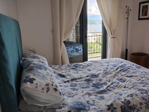 ein Bett mit einer blauen und weißen Bettdecke und einem Fenster in der Unterkunft Monteview Duplex in Herceg-Novi