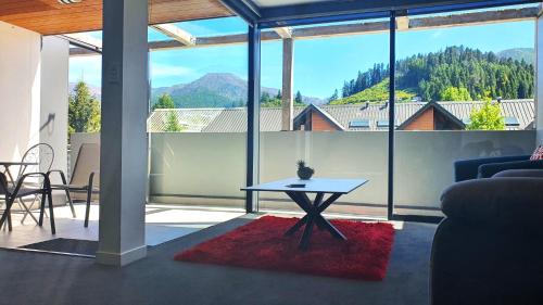 a living room with a table in front of a large window at Central Apartment in Hanmer Springs