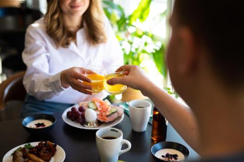 a woman sitting at a table with two glasses of orange juice at Best Western Hotel Varnamo in Värnamo