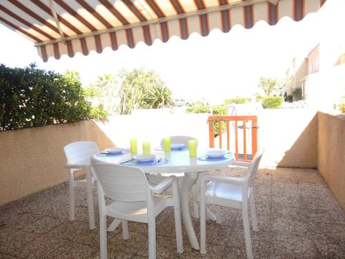 une table blanche et des chaises sur une terrasse dans l'établissement Maison 2 pièces avec mezzanine, accès direct plage, terrasse, parking, 6 couchages, animaux acceptés. - FR-1-229D-124, à Saint Pierre La Mer