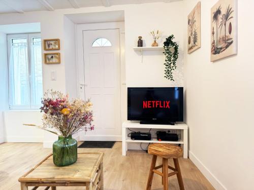 ein Wohnzimmer mit Fernseher und Tisch in der Unterkunft Maisonnette cocon hyper-centre in Fontenay-le-Comte
