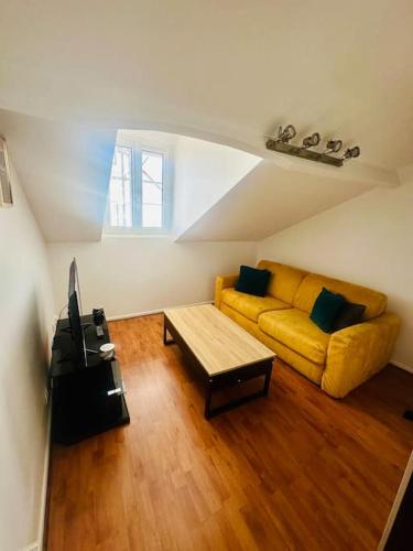 马恩河畔莱佩尔勒Studio Le Cocon détente proche Paris Disney的客厅里有一张黄色的沙发和一张桌子