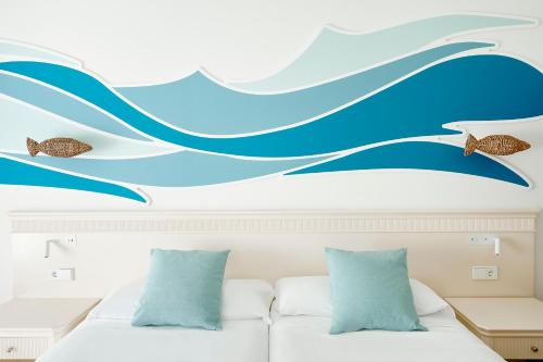 a bedroom with a bed with a blue wave wall mural at Iberostar Waves Gaviotas Park in Morro del Jable