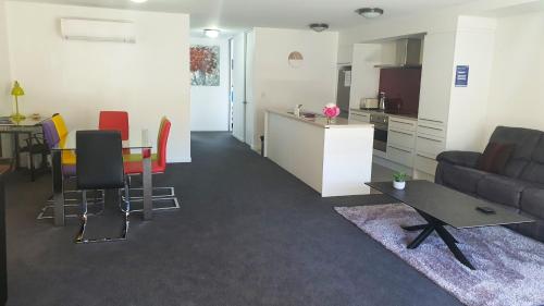 a living room with a couch and a table and a kitchen at Central Apartment in Hanmer Springs