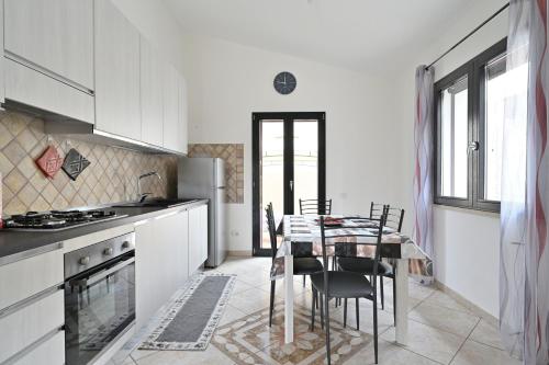 eine Küche mit einem Tisch und Stühlen sowie eine Küche mit weißen Schränken in der Unterkunft Casa Bari Sardo per più famiglie in Bari Sardo