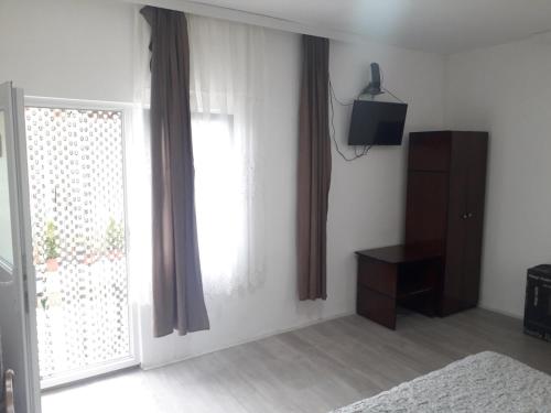 sypialnia z łóżkiem, telewizorem i oknem w obiekcie Apartmani Zivkovic w mieście Ribarska Banja