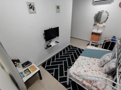 um pequeno quarto com uma cama e uma televisão em Sri MaLati Homestay and Event Space em Balik Pulau