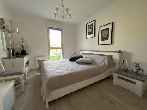 - une chambre blanche avec un lit et un lustre dans l'établissement Appartement calme, jardin, 4 pers, Proche plage et commerces, Parking, Normes Handicapés - FR-1-494-167, à Royan