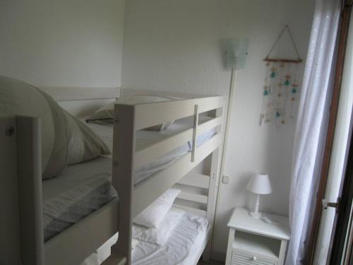 Ce lit superposé blanc se trouve dans un dortoir doté d'une lampe. dans l'établissement Saint-Cyprien: T2 cabine rénové 6 pers, piscine, parking, à 100m de la plage - FR-1-106-80, à Saint-Cyprien