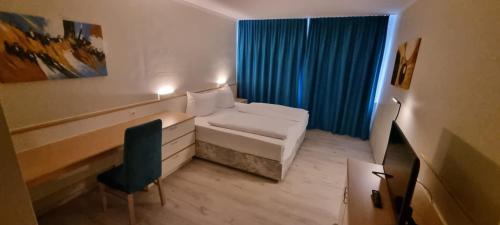 Hotel B99 في أوفنباخ: غرفة صغيرة بسرير وستارة زرقاء
