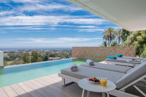 a villa with a swimming pool and a balcony with chairs at Remarkable 2021-Built Luxury Villa in El Herrojo in Benahavís