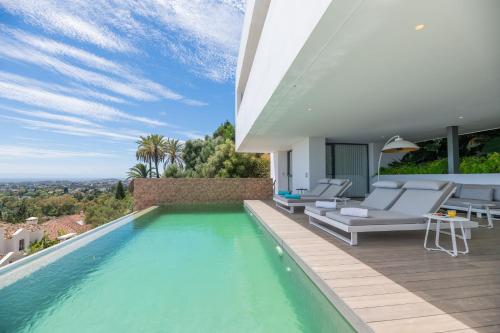 a swimming pool with chairs and a house at Remarkable 2021-Built Luxury Villa in El Herrojo in Benahavís