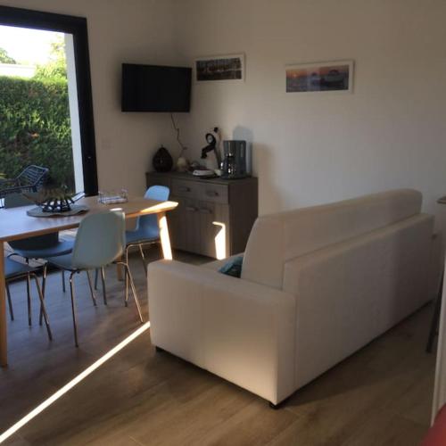 un salon avec un canapé blanc et une table dans l'établissement Joli studio de 25m2 avec terrasse, idéal pour un couple, à Gujan-Mestras