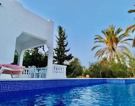 een zwembad met een prieel naast een zwembad bij Villa Chaâbane in Djerba