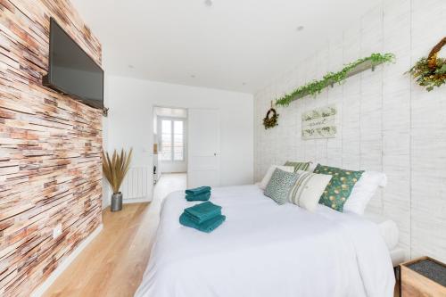 une chambre avec un lit blanc et un mur de briques dans l'établissement JO 2024 - Face au métro 13 - 26 m2 refait à neuf, à Saint-Ouen